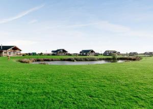 a small pond in a field with houses in the background at Hornsea Lakeside Lodges in Hornsea