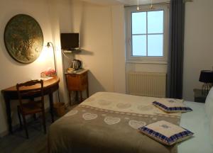 a bedroom with a bed and a desk and a window at Au Fief du Château in Orschwiller