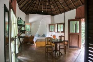 1 dormitorio con 1 cama, mesa y sillas en Jolie Jungle Eco Hotel, en Puerto Morelos