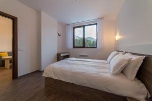 a bedroom with a large white bed with a window at From Sunrise to Sunset at Oak Residence Smolyan Lakes in Pamporovo