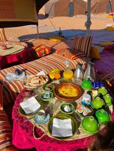 a table with plates of food on a blanket at Bivouac Luna in Mhamid