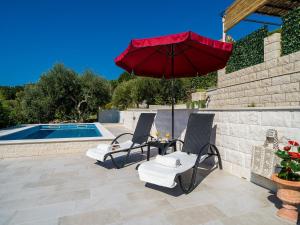 un patio con 2 sillas y una sombrilla junto a la piscina en Villa Melita, en Trsteno