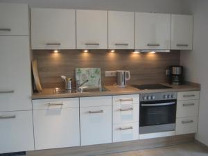 a kitchen with white cabinets and a sink at Appartements Buesum DS10 in Büsum