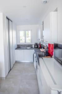 a white kitchen with white cabinets and a sink at LA FREGATE Maison avec piscine/parking/wifi/plages 5kms in Les Mathes
