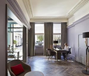 a woman sitting at a desk in a room at Signature Townhouse London Hyde Park in London