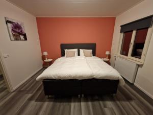 - une chambre avec un grand lit aux murs orange dans l'établissement B&B gewoon Prins, à Wichmond