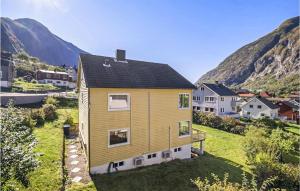 a yellow house on a hill with mountains in the background at Cozy Apartment In rdalstangen With Wifi in Årdalstangen