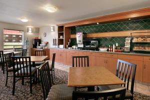 a restaurant with tables and a counter with a kitchen at Super 8 by Wyndham Slave Lake AB in Slave Lake