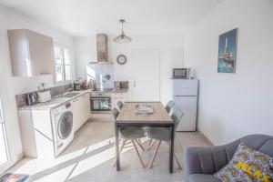 a kitchen with a table and a kitchen with a washing machine at LE MOUSSE Maison avec piscine/parking/wifi/plages 5kms in Les Mathes