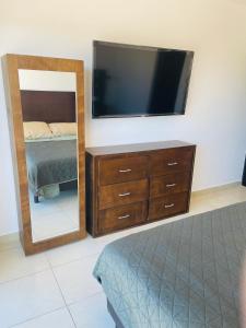 a bedroom with a tv and a dresser with a mirror at Nuevo departamento a solo 3 min de la playa con todos los servicios in La Florida