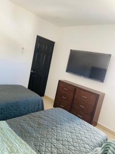 um quarto com 2 camas e uma televisão de ecrã plano em Nuevo departamento a solo 3 min de la playa con todos los servicios em La Florida