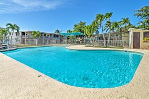 a swimming pool with blue water and palm trees at Coastal Puerto Rican Apartment - Walk to Beach! in Rio Grande