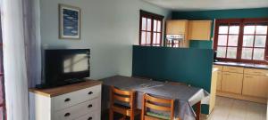 a kitchen with a table and a tv on a counter at Le Bout des Dunes, baie de Somme in Saint-Quentin-en-Tourmont