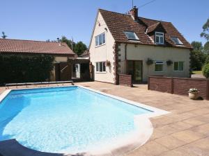 a large swimming pool in front of a house at Linnets in Fitzhead