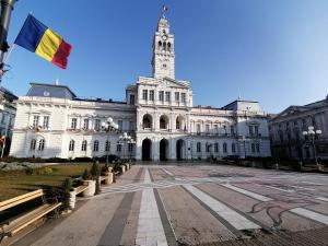 a large white building with a clock tower and a flag at Casa Clau in Arad