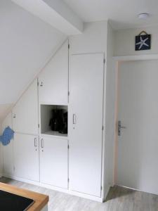 a white cupboard in a room with a staircase at Ferienwohnung: Utkiek in Langeoog