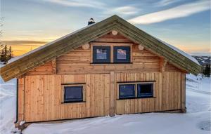 uma cabana de madeira na neve com duas janelas em Awesome Home In yer With Kitchen em Hafjell