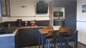 - une cuisine avec une table en bois et deux tabourets de bar dans l'établissement Suite Deluxe, calme proche Airbus et Chantiers de l'Atlantique, à Saint-Nazaire