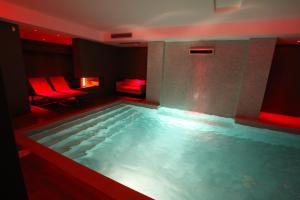 una gran piscina en una habitación con luces rojas en Alysa - Suite Wellness & Spa, en Giarre