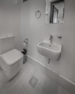 a white bathroom with a toilet and a sink at Go Camp Mountain Nature Lodge مخيم الطبيعة الجبلية in Sharīyah