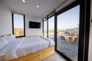 a bedroom with a bed and a large window at Go Camp Mountain Nature Lodge مخيم الطبيعة الجبلية in Sharīyah