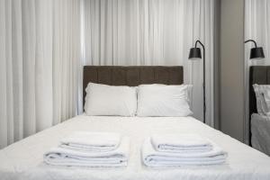 Una cama con tres toallas apiladas encima. en ZEE Studios a 200m da beira-mar norte, en Florianópolis