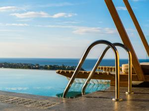 a wooden bench next to a body of water at Mani Theasis in Stoupa