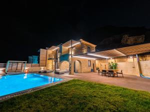 a house with a swimming pool at night at Mani Theasis in Stoupa
