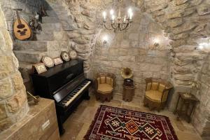 Abū Ghaush的住宿－Palace of Sultan Jalal Basha，一间设有钢琴和椅子的石墙客房
