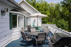 un patio con mesa, sillas y parrilla en Longhouse Manor B&B, en Watkins Glen