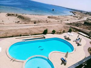ein Schwimmbad mit Strand im Hintergrund in der Unterkunft Doudy in Sharm El Sheikh