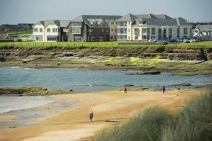 a group of people standing on a beach near the water at Atlantic Coast Lodge in Spanish Point