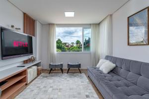 uma sala de estar com um sofá e uma televisão em Apto Maestria - Stay House em Gramado