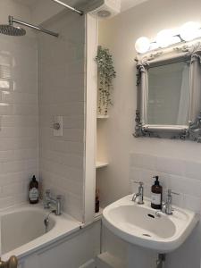 a bathroom with a sink and a tub and a mirror at Ashcroft Hall - Converted Chapel in Central Cirencester in Cirencester