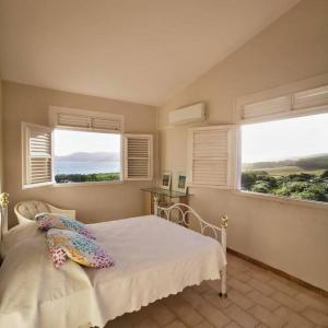a bedroom with two windows and a bed with pillows at Vue sur mer à la Villa Parme in Le Robert