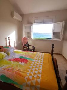 a bedroom with a bed with a colorful quilt on it at Vue sur mer à la Villa Parme in Le Robert