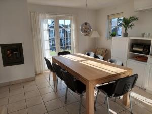 cocina y comedor con mesa de madera y sillas en Wounderful holiday house with wifi, spa & sauna, en Gjern