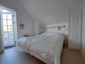 Dormitorio blanco con cama y puerta abierta en Wounderful holiday house with wifi, spa & sauna, en Gjern