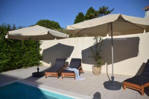 Un grupo de sillas y sombrillas junto a una piscina. en Casas Cerejas, en Serra de Mangues