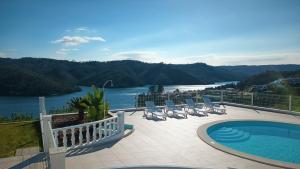 a swimming pool with chairs and a view of a river at Lago Azul Villas in Ferreira do Zêzere