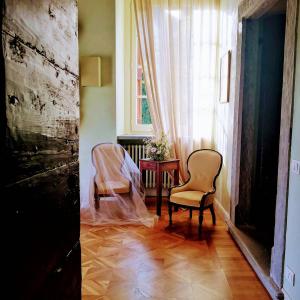 B&B Dimora Delle Donnole Bergamo Alta في بيرغامو: غرفة بها كرسيين وطاولة ونافذة