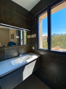 a bathroom with a white sink and a window at Casa u fornu Residence & Spa in LʼÎle-Rousse