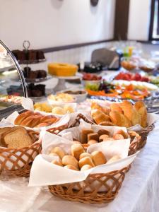 a table with baskets of bread and pastries on it at Pousada O Cantinho da Raposa in Monte Verde