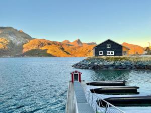 un muelle con una casa y barcos en un lago en Fishermans Rorbu 2 - Lofoten, en Ramberg