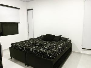 a black bed in a white room with a television at Villa Nila in Carmen de Apicalá