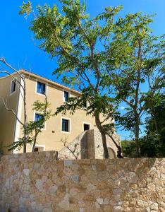 um edifício atrás de uma parede de pedra com uma árvore em Casa u fornu Residence & Spa em LʼÎle-Rousse