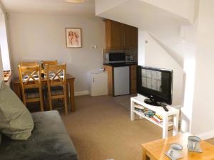 a living room with a tv and a kitchen at Quiet Country Annex - Near M1 - J27 in Selston