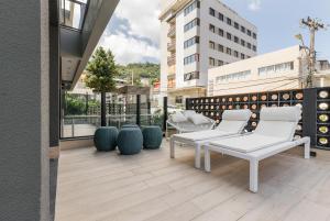 balcón con sillas blancas y vistas a un edificio en ZEE Studios a 200m da beira-mar norte, en Florianópolis