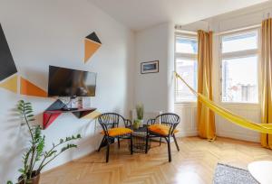een woonkamer met een tafel en stoelen en een televisie bij Art Downtown Home styled by a Local Designer in Boedapest