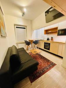 a living room with a black couch and a kitchen at Exklusives Apartment nahe VW-Halle in Braunschweig